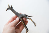 Vintage bronze African giraffe held in hand showing its scale and textured patina.