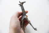 Slender vintage bronze giraffe held in hand to show its textured patina.