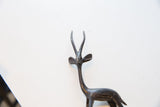 Close-up of a vintage African gazelle figurine's head, textured horns, and dark patina.