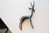 Vintage left facing African gazelle figurine, dark metallic with textured patina from above.