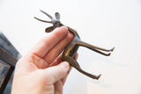 A hand holding the vintage gazelle table accent, showing its size and aged patina.