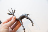 Vintage African gazelle sculpture held in hand, showing its scale and dark metal patina.