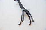 Angled view of the vintage giraffe's slender dark bronze legs and stance.