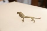 Profile view of a vintage African lion showing its slender body and oxidized patina.