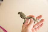 Hand holding the small vintage African lion to show its scale and oxidized finish.