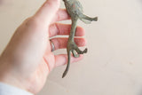 Profile of the oxidized lion figurine showing its slender legs and long tail.