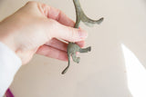 A hand holding the vintage lioness figurine to show the detail of its oxidized legs.