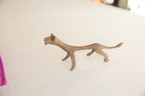 The elongated form and rustic metal texture of a vintage African lioness figurine.