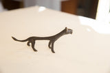 The slender silhouette of a vintage African cheetah statuette with dark patina.