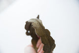 Textured rope detail and aged patina along the vintage cuff's scalloped edge.