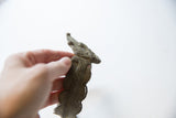 A hand holding the detailed snake head of a vintage African cuff.