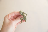 A small bronze monkey figurine with aged patina held for scale.
