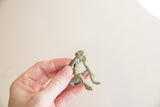 Vintage African bronze monkey with a green patina held to show its scale.