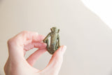 The back of a vintage African bronze monkey, showing its slender form and aged patina.