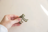 Hand holding a vintage African bronze monkey, revealing its textured green patina.