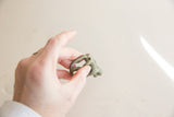 Vintage African bronze monkey in hand, displaying its time-softened green patina.