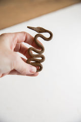 The textured, coiled body of a vintage iron snake held in hand for scale.