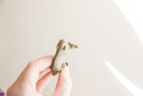 Small vintage African bronze monkey held in hand, showing its aged texture and scale.