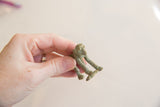 Small African bronze monkey held to display its aged texture and green patina from the side.
