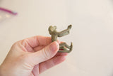 Side view of a vintage bronze monkey, highlighting its stylized pose and aged patina.