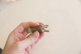 Underside view of the small bronze monkey showing the hollow casting and looped tail.