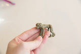 Hand holding vintage African bronze monkey, showing aged verdigris patina.