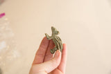 Small African porcupine sculpture with oxidized patina held to show scale and detailed texture.