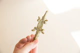 Vintage bronze crocodile held in hand, showing its textured patina and small size.