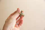 Small vintage bronze impala figurine held in hand, showing its textured, aged patina.
