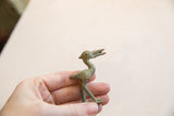Vintage bronze bird sculpture held in hand to show its petite scale and aged patina.