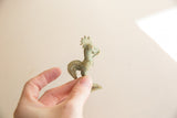 A small vintage African bronze rooster with green patina held in hand.