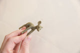 Hand holding the vintage African Impala gold weight, showing textured green patina.