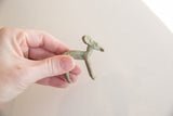 Small vintage African impala gold weight with a green patina held in hand for scale.