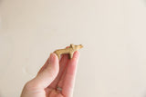 Vintage African brass hippo held in hand, showing its small scale and simple form.