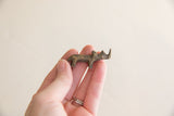 Vintage African brass mini rhino held in a hand, showcasing its aged metallic finish.