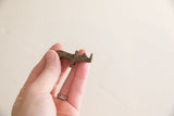 Vintage African brass mini rhino with time-softened tones and rough texture.