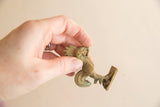 Vintage African bronze rooster held in hand, illustrating its small size and detailed texture.