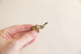 Vintage African mini elephant held to show its small scale and weathered, dark patina.