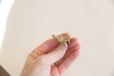 A hand holds the vintage mini elephant, showing its small scale and aged patina.