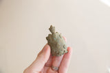 Vintage oxidized African turtle held in hand, showing the profile and textured spiral shell.