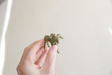 Hand-held view of the vintage impala ram gold weight showing its scale and patina.