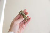 Weathered patina and sculpted form of a vintage impala ram gold weight held for scale.