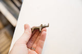 A small vintage bronze rhino figurine held in hand to show its scale and aged patina.