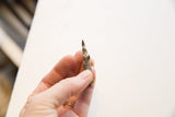 Side view of the miniature bronze rhino held to show its scale and vintage texture.