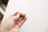 Vintage African bronze mini rhino held in hand to show its small scale.