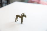 Vintage cast metal impala ram gold weight with curved horns and a weathered finish.