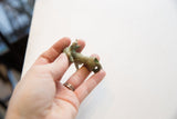 Vintage African impala ram gold weight held in hand to show its scale and patina.