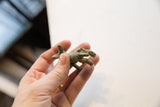 Hand holding the vintage African rabbit gold weight with aged patina.