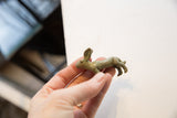 Vintage African rabbit gold weight held in hand, revealing its distinct side profile and patina.