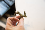 Vintage African rabbit gold weight in hand, showing its rich green patina.